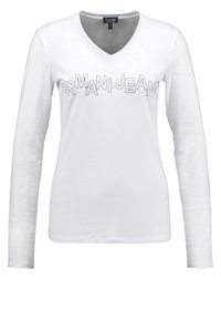 Bílá dlouhá košile s véčkovým výstřihem vyrobená z měkké tkaniny, s texturovaným logem "ARMANI JEANS" přes hrudník v lesklém stříbrném provedení.