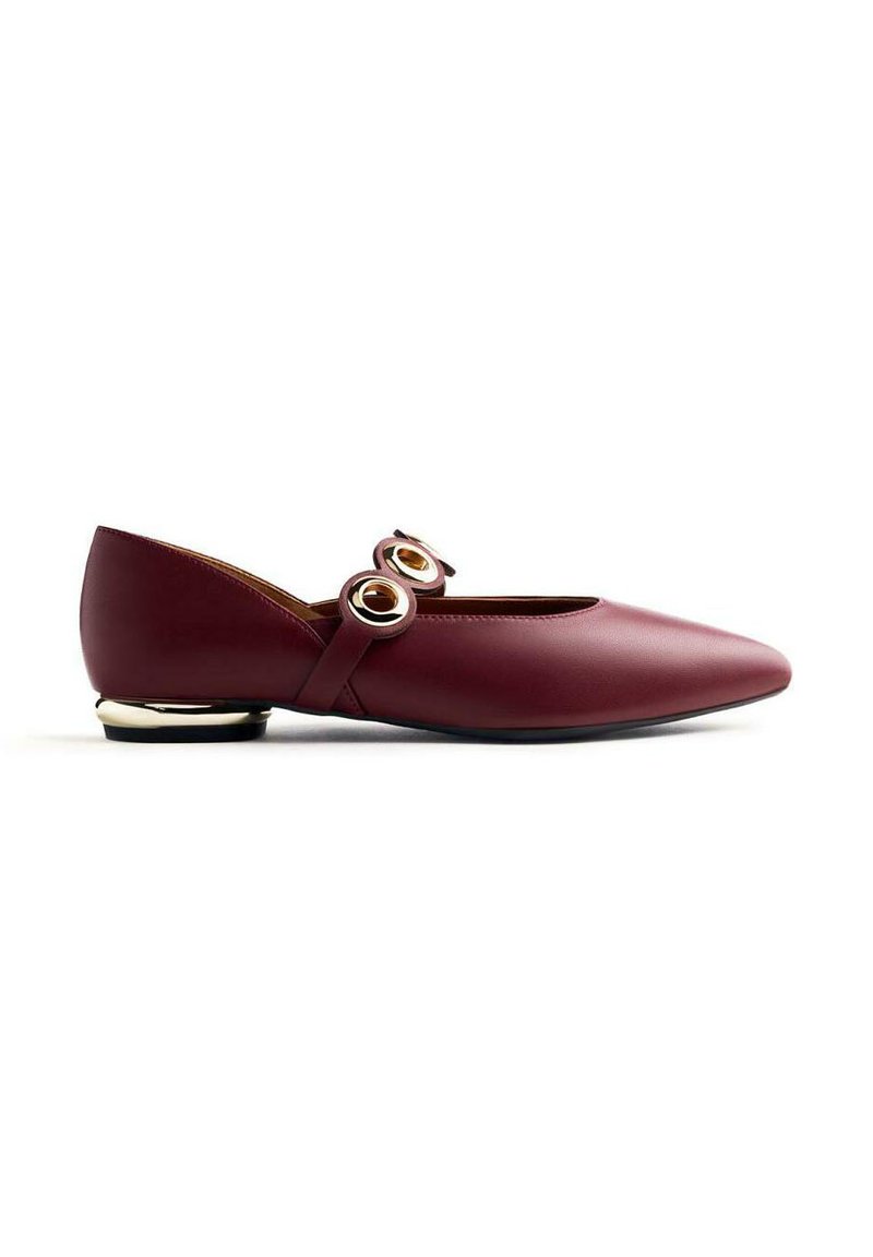 Chaussure plate en cuir bordeaux avec un bout pointu, deux accents ronds dorés sur la sangle et un petit talon doré. Texture lisse et design épuré.