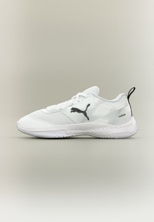 Biely športový topánka Puma Varion s čiernym logom a sťahovacou pútkom, textúrovanou podrážkou a sieťovinovým a syntetickým zvrškom.