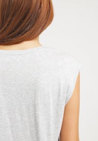 Gray cap sleeve top made of soft, lightweight fabric. Features a relaxed fit with a round neckline, showing smooth texture and simple design.