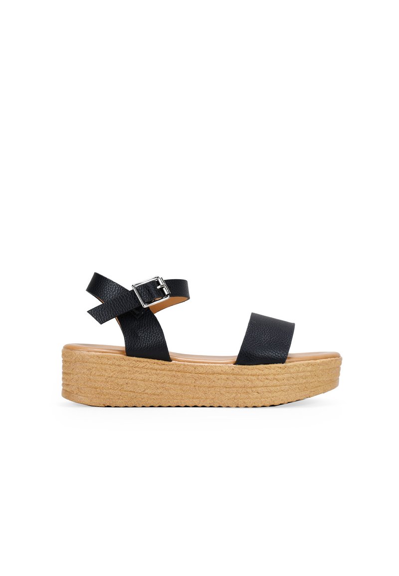 Black wedge sandals with textured straps and a buckle. Natural woven sole with a slight elevation, smooth footbed, and minimalist design.