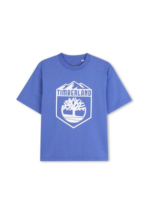 T-shirt in cotone blu con logo Timberland stampato in bianco all'interno di un design a scudo, con grafiche di montagne sopra e un motivo di albero sotto.