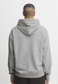 Sudadera gris con un corte relajado, capucha con cordón y puños y dobladillo acanalados. Tejido suave con detalles de costura mínimos.