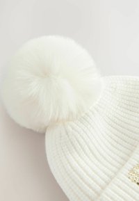 White knitted beanie with a large white faux fur pom-pom on top. Features ribbed texture and a sparkling accent detail near the brim.
