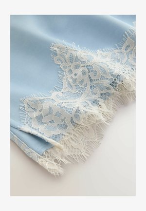 Delicato bordo in pizzo floreale bianco su tessuto azzurro chiaro morbido, caratterizzato da una rete intricata e bordi sfrangiati smerlati.