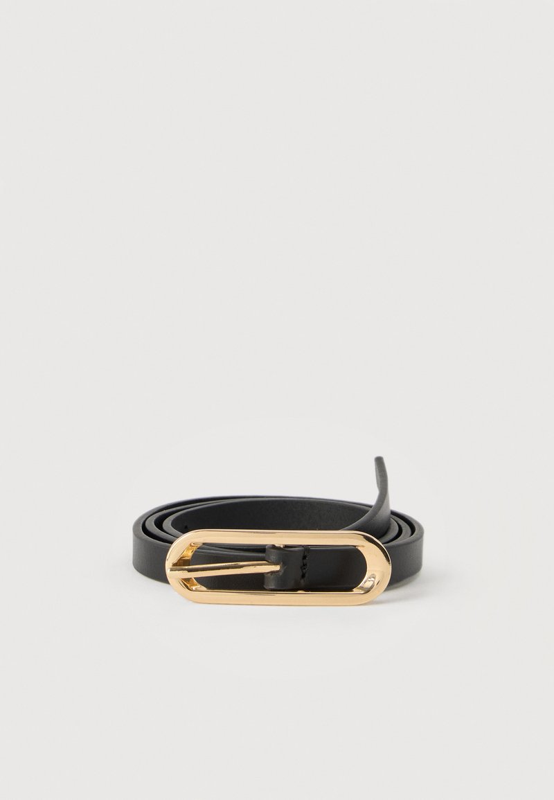 Ceinture en cuir noir enroulée avec une boucle ovale allongée brillante en or sur un fond blanc.