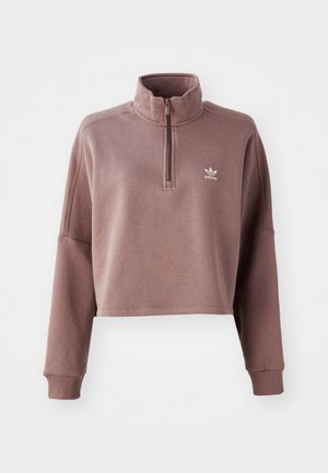 Cropped pullover in muted mauve, made of soft fabric. Features a quarter-zip mock neck, long sleeves, and a small white logo on the chest.