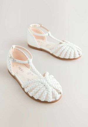 Hvide flet-sandaler med T-rem, åben tå og lys brun sål med polstrede indlæg. Ideelle til afslappet brug.