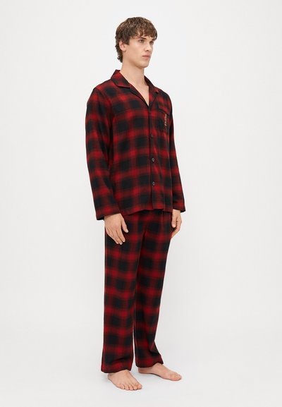 Pijama u crveno-crnoj kariranoj šabloni od mekog materijala; sadrži košulju na dugmad s džepom i hlače širokog kroja.