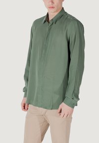 Camicia verde a maniche lunghe, tessuto leggero, chiusura frontale con bottoni, colletto, polsini con un bottone, texture liscia, orlo dritto.