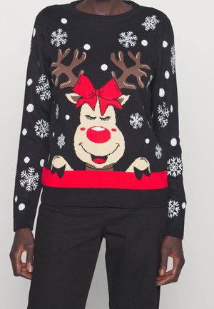 Persona que lleva un jersey negro de Navidad con la cara sonriente de un reno, nariz roja y lazo, rodeada de copos de nieve y puntos blancos.