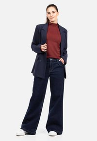 Meresinine bleiser bordoopunase kaelusega, kombineeritud laia säärega tume teksapükstega ja valgete tossudega, rõhutades puhtaid jooni ja kaasaegset lõiget.