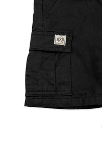 Svarta cargoshorts med en framficka, ficka med lock på sidan och en vävd etikett med korsade pilar. Tillverkade av hållbart material.