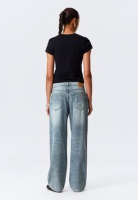 Black fitted t-shirt paired with light blue wide-leg denim jeans, featuring a slightly distressed texture and rear pockets, viewed from the back.