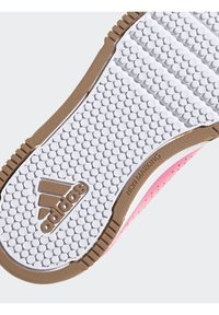 Suola di sneaker Adidas con una superficie testurizzata bianca e impugnature circolari, bordo in gomma marrone e accenti rosa nella sezione superiore.