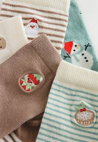 Calze festive colorate decorate con vari motivi ricamati: Babbo Natale, pupazzo di neve e fantasie festive, con texture e righe in materiali morbidi.