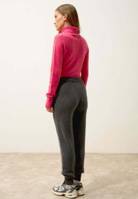Fitted rosa polotröja med ribbat mönster, kombinerad med mörkgrå avsmalnande sweatpants. Bärs med casual gråa och krämfärgade sneakers.