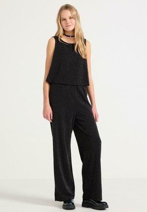 Zwarte jumpsuit met een mouwloos ontwerp, losse pasvorm en een sprankelende textuur. Heeft een cropped toplaag en wijde broekspijpen, gecombineerd met chunky schoenen.