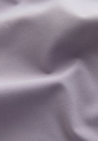 Blødt, tekstureret stof i en lys lavendelfarve, der viser subtile folder og glathed, hvilket fremhæver dets stræk og fald.