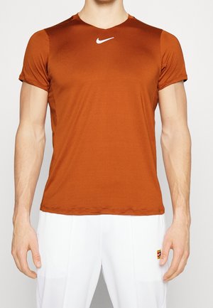 Camiseta deportiva naranja de Nike hecha de tejido ligero, con escote en V y mangas cortas, y un pequeño logo blanco en el pecho.