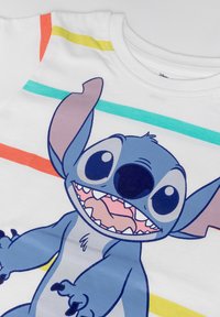 White cotton T-shirt featuring a colorful striped design with a large blue cartoon character, Stitch, in a smiling pose.