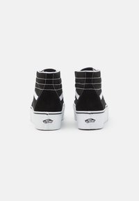 Zwarte high-top sneakers van suede met witte rubberen zolen, voorzien van witte zijstripes en contrasterende stiksels. Logo zichtbaar op de hak.
