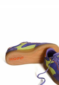 Zapatillas con ante púrpura y verde, suela de goma, detalles en naranja, parte superior texturizada y cordones visibles. Logo "HOFF" en la suela.