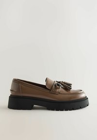Bruna läderloafers med rund tå, med en dekorativ tofs och svart kraftig sula med strukturerat mönster.