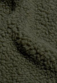 Donkergroene fleece stof met een gestructureerd, zacht oppervlak, met een pool en een licht gerimpeld uiterlijk.