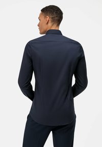 Marineblauw overhemd met lange mouwen, gladde textuur, klassieke kraag, rechte achterkant, met subtiele zijnaaddetail en knoopmanchetten.