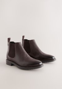 Brune Chelsea-støvler i læder med elastiske sidepaneler, tekstureret finish, rundet tå og lav stabelhæl. Har trækflapper for nem påtagning.