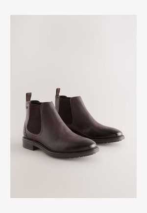 Braune Chelsea-Stiefel aus Leder mit elastischen Seitenpartien, strukturierter Oberfläche, abgerundetem Zehenbereich und niedrigem Blockabsatz. Ausgestattet mit Laschen zum einfachen An- und Ausziehen.