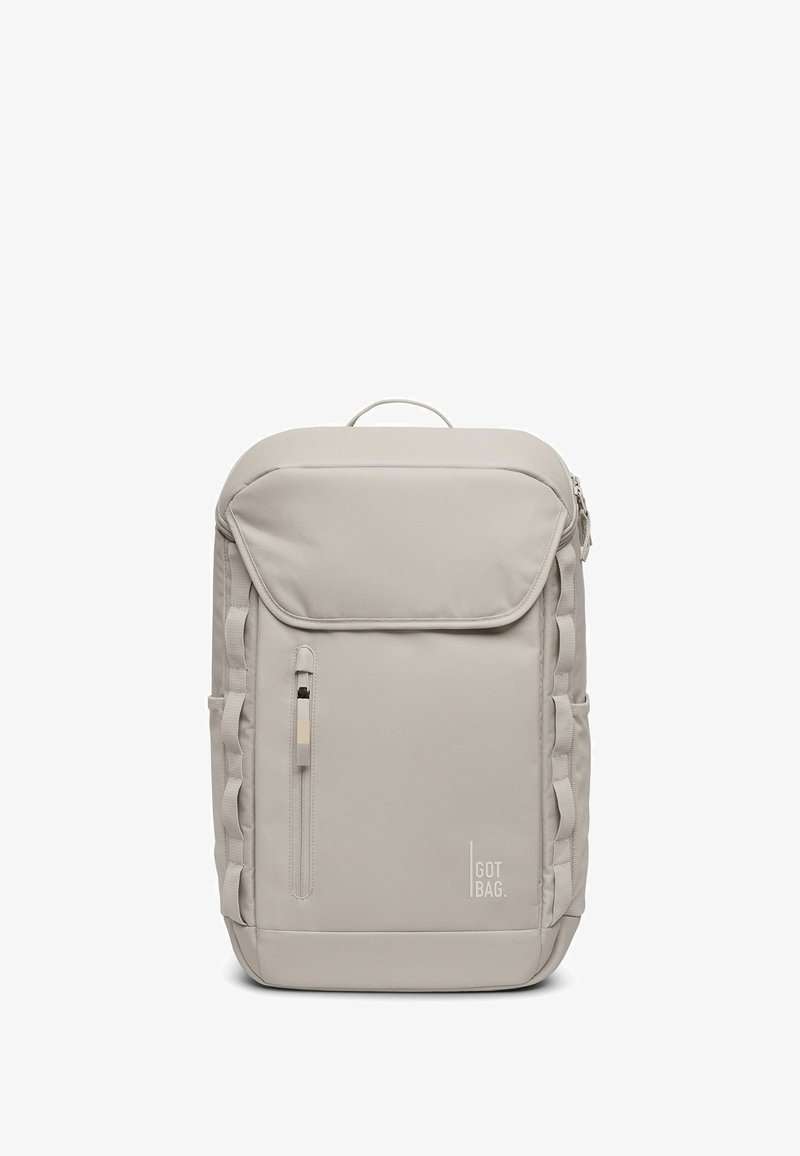 Zaino grigio chiaro realizzato con un tessuto liscio e resistente. Presenta una tasca frontale con zip, cinghie laterali e un manico superiore per il trasporto.