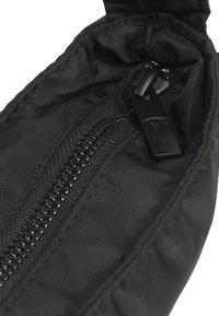Gros plan d'une fermeture éclair en tissu noir avec une tirette noire sur un vêtement ou un sac.