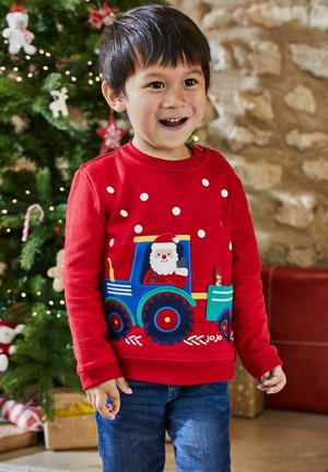 Rød sweater med hvide prikker, der har en broderet blå traktor, julemand, og farverige detaljer. Blød tekstur, lange ærmer, rund hals.