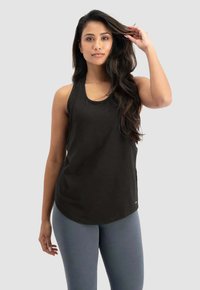 Schwarzes sportliches Tanktop mit Rundhalsausschnitt, weichem Material und lässiger Passform. Kombiniert mit hellgrauen Leggings, die minimalistisch gebrandet sind.