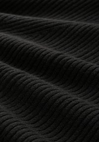 Schwarzer strukturierter Stoff mit vertikalem Rippmuster, der eine weiche, plüschige Beschaffenheit und ein einheitliches Erscheinungsbild zeigt.