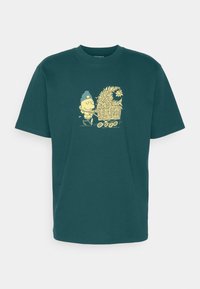 Teal bomulds T-shirt med et gult design af en smilende person, der skubber en vogn fyldt med blomster og planter. Korte ærmer og rund hals.
