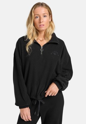 Zwarte geribbelde pullover met een kwart-ritsontwerp, elastische manchetten, trekkoord in de taille en een subtiel geborduurd logo op de borst.