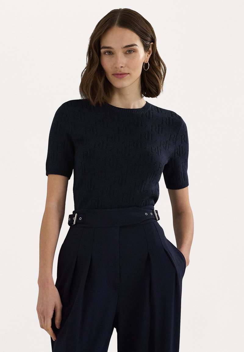 Μαύρη πλεκτή μπλούζα κοντό μανίκι με υφή. Συνδυασμένη με ψηλόμεσες παντελόνες που διαθέτουν λεπτομέρεια με πόρπη.