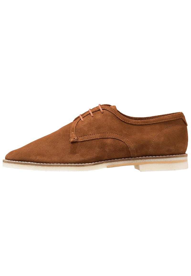 Chaussure en daim marron avec un bout arrondi, un design à lacets et une semelle de couleur claire. Texture douce avec peu de détails et des accents cousus.