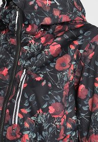 Veste noire avec un motif floral rouge et rose, équipée d'une fermeture éclair blanche et d'une capuche réglable avec cordons.