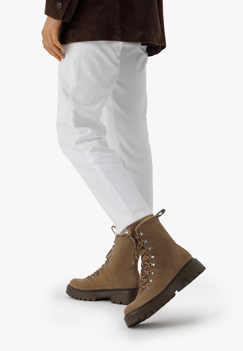 Ruske nubuk ankle boots s metalnim okovima i pertlama, sa debelim gumene potplate i teksturiranim završetkom. Uparen s belim hlačama.