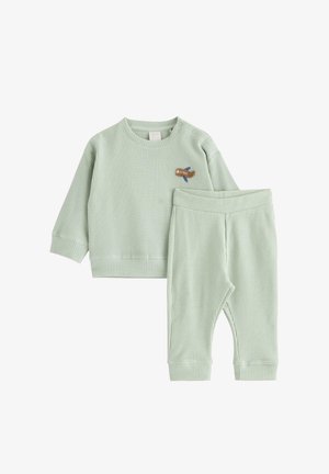 Hellgrünes, waffelgestricktes Langarmshirt für Kleinkinder mit Druckknöpfen und Hose, mit kleinem Flugzeug-Patch auf der Brust.