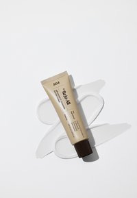Dr.Reju-All Advanced Ceramide Barrier crèmetube op een witte ondergrond met crème in een draaikolk eronder die de belangrijkste ingrediënten en productnaam benadrukt.