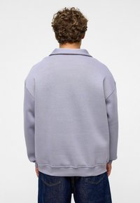 Lichtpaarse sweatshirt met een ontspannen pasvorm, verlaagde schouders en een geribbelde zoom. Gemaakt van een zachte stof, gezien vanuit de achterkant.