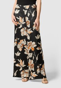 Pantalons larges en tissu noir avec des motifs de fleurs orange et beige. Présente une taille plate et une texture lisse.