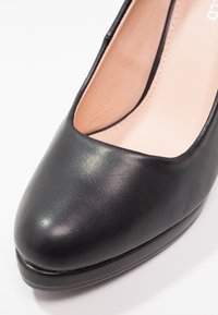 Chaussure femme en cuir noir à bout fermé avec un avant carré arrondi et une doublure intérieure beige clair, vue en angle haut-avant.