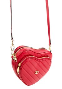 Sac bandoulière en cuir rouge en forme de cœur avec un design matelassé, des fermetures éclair dorées et un détail de logo, suspendu par une fine bandoulière réglable.
