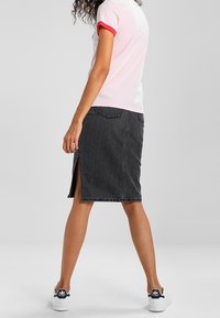 Svart denimkjol med en framficka, medellång design och två bakfickor. Kombinerad med en t-shirt i rosa och vitt och vita sneakers.